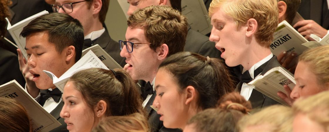 faces of students singing in choir on stage