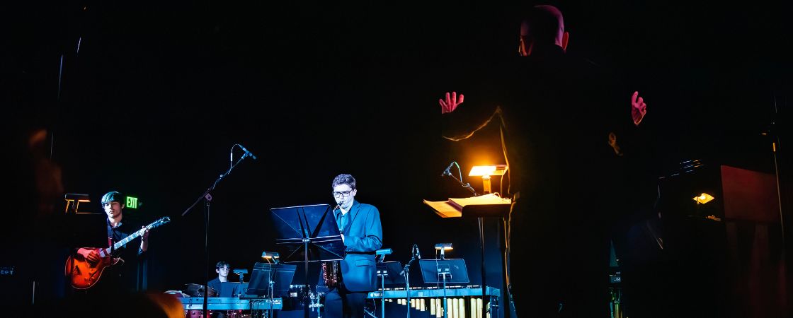 2 students playing instruments on stage and director