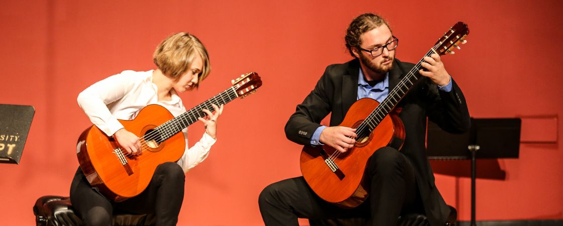 2 students playing guitars on stage