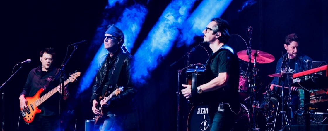 four white males playing instruments on stage