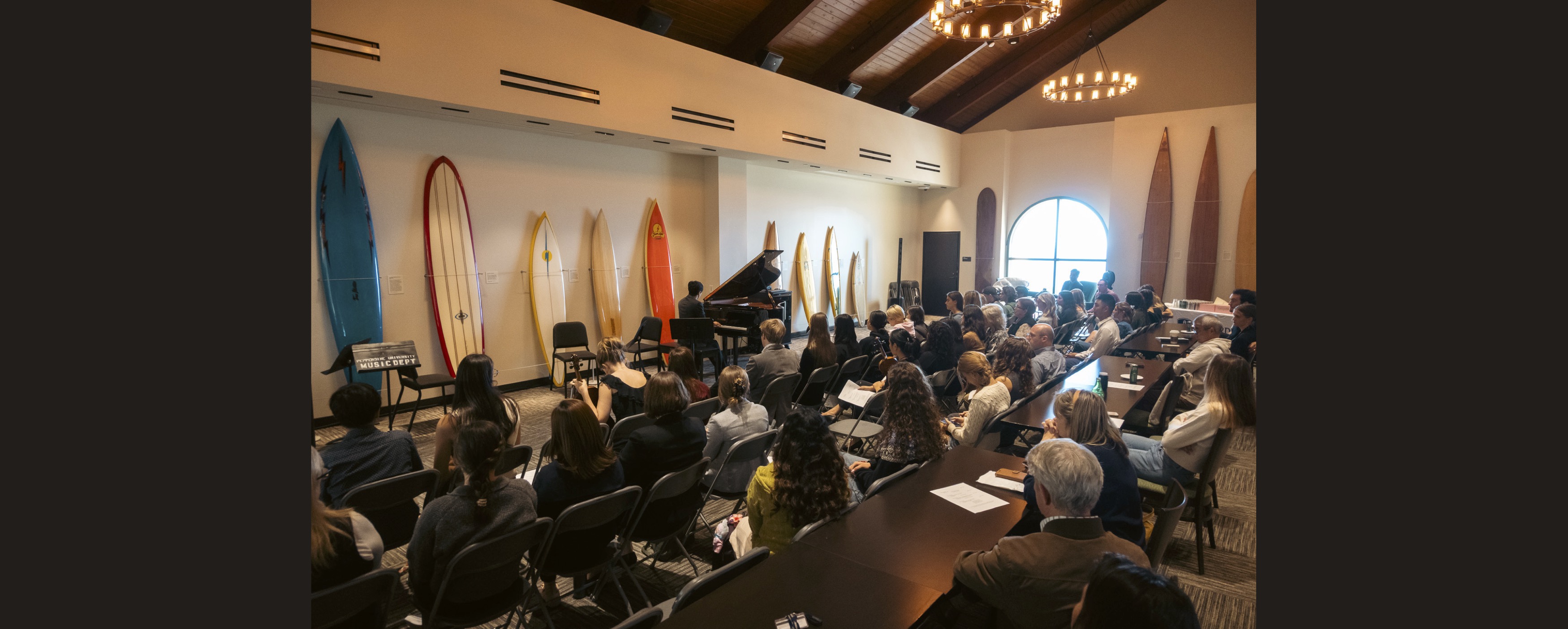 A seated audience regards pianist Barry Tan as he performs in Pepperdine Library's Surfboard Room