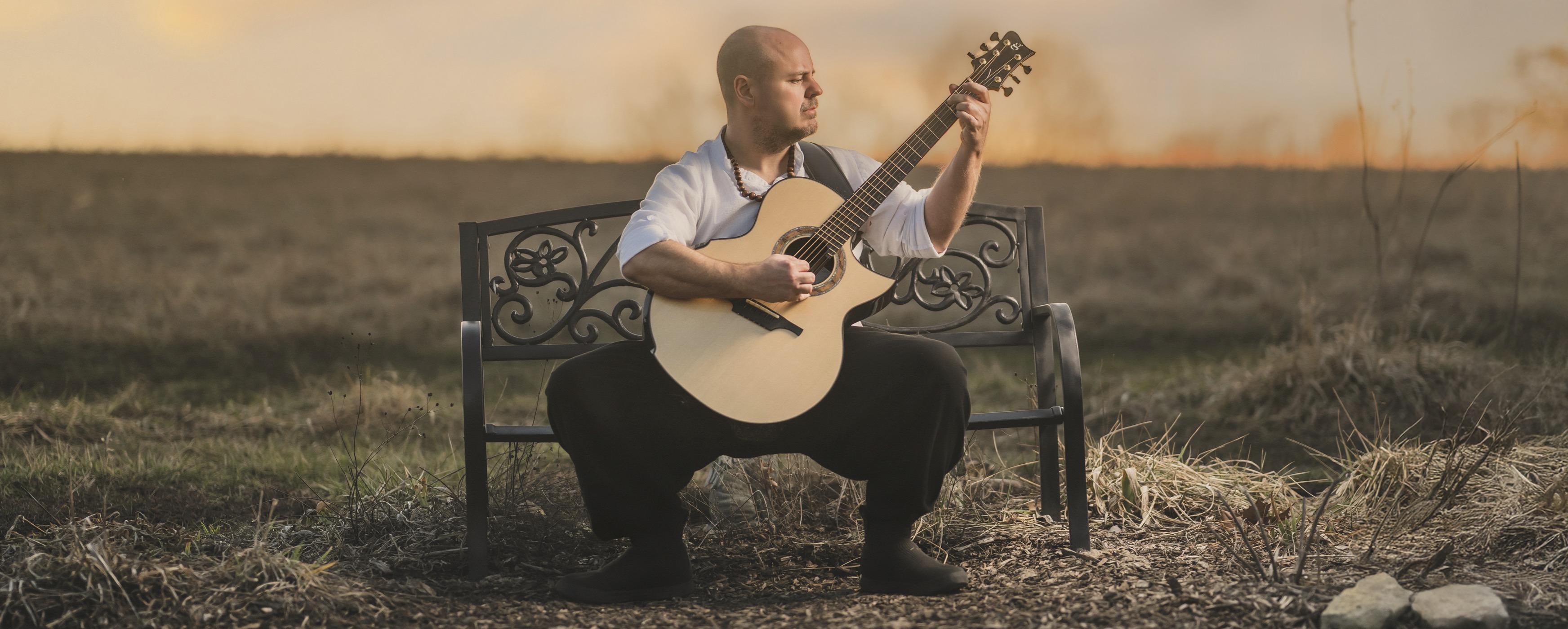 man playing guitar on bench