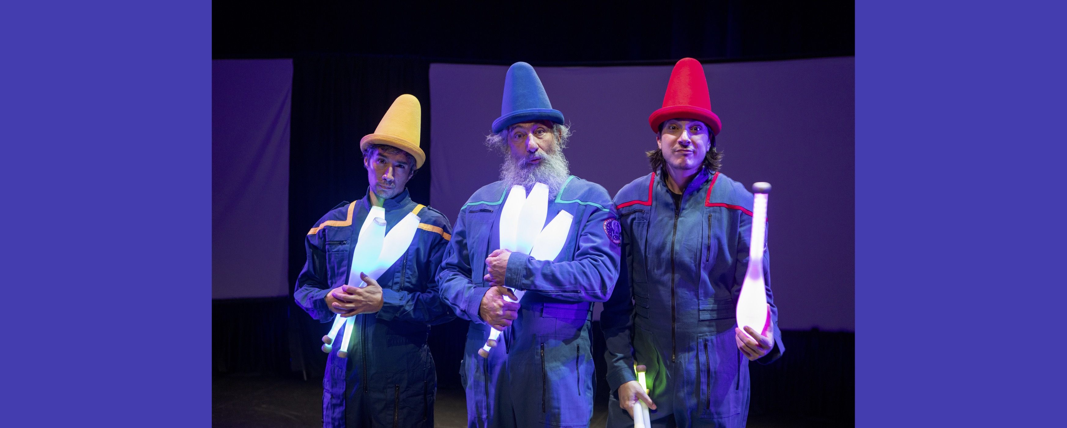 Image of the three Flying Karamazov Brothers in silly hats with juggling pins