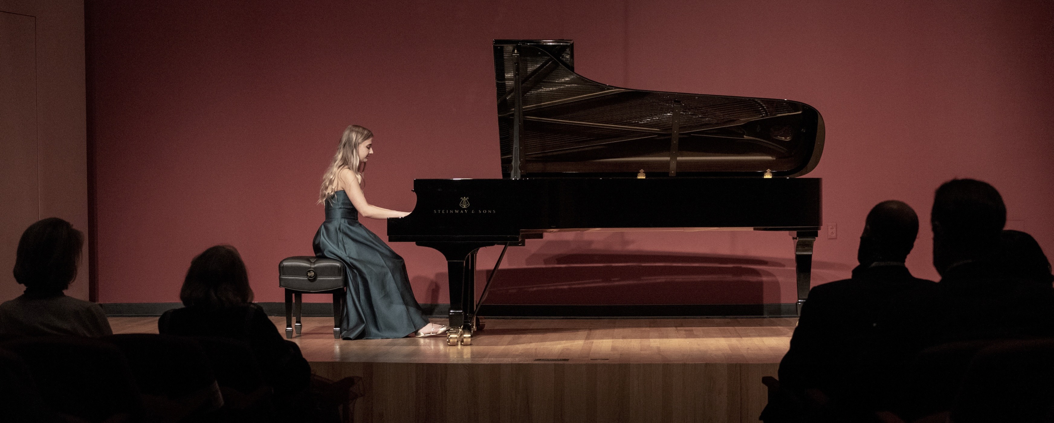 Image of piano student in formal dress playing piano in Raitt Recital Hall