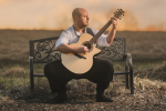 Andy McKee with guitar on bench 
