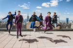 Broadway Boys jump into the air in front of a skyline view of New York City
