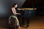 Chaeyoung Park seated next to a piano in a colorful dress