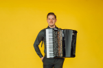 Radu Ratoi poses with accordion on yellow background