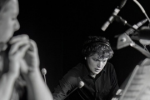 Image of student playing instrument in the foreground while another student focuses intently on an instrument in the background
