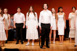 image of student performers singing in coordinated outfits on stage