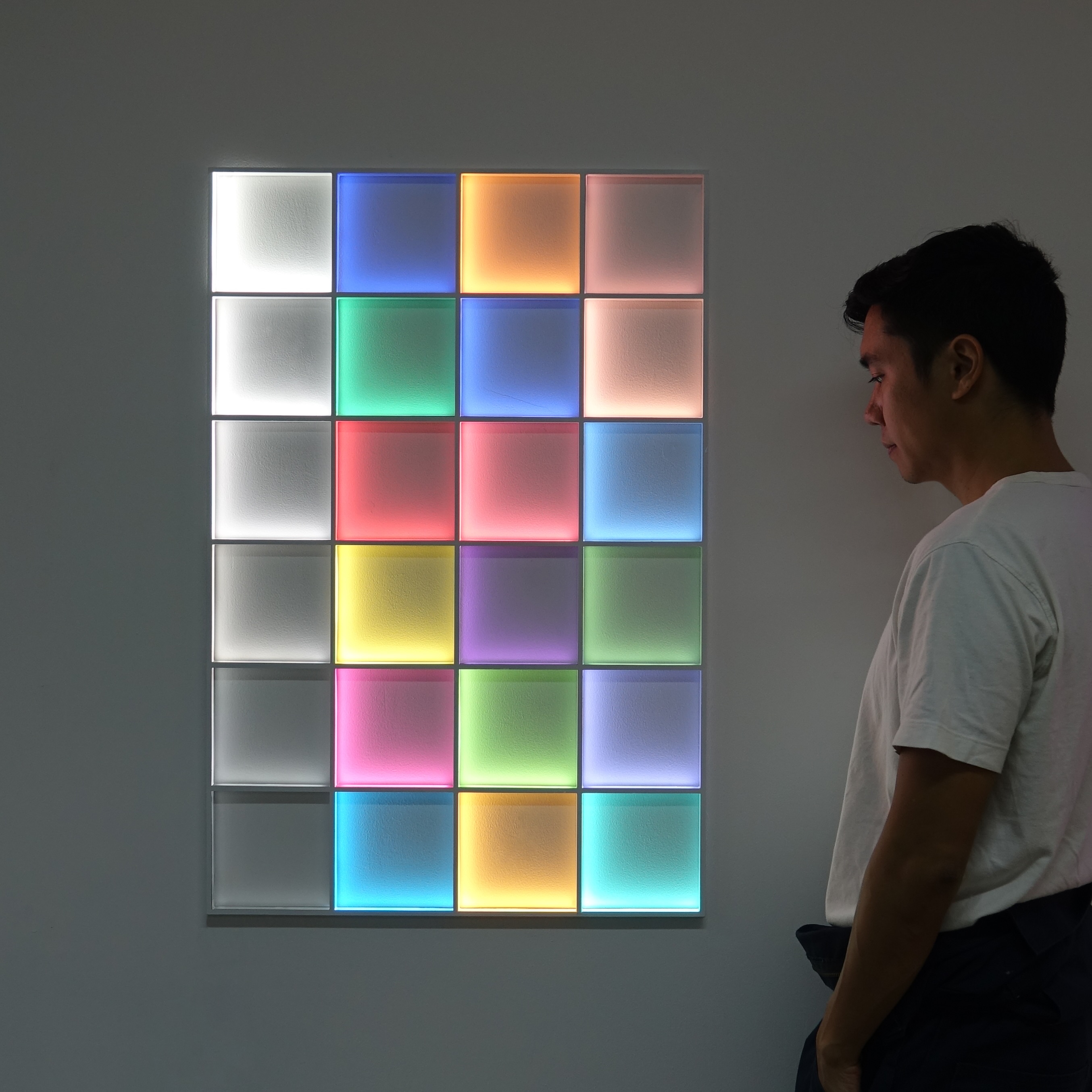 Man looking at colorful squares that are light up on a wall